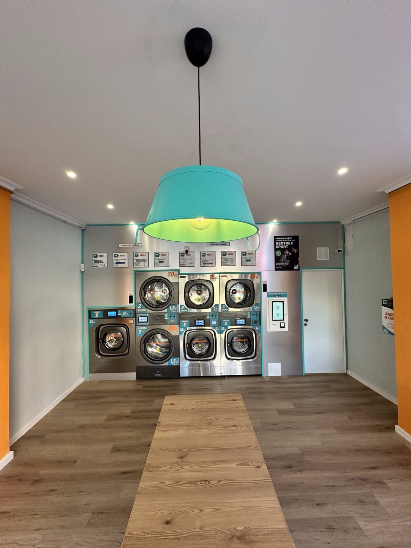 Lavandería Seco y Espuma Fuengirola Interior de Lavandería Seco y Espuma Fuengirola con mesas, bancos y máquinas de lavandería. Luz tenue y decoración moderna.